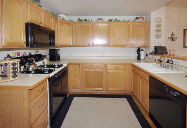 Kitchen with large pantry, black appliances, and hardwood flooring