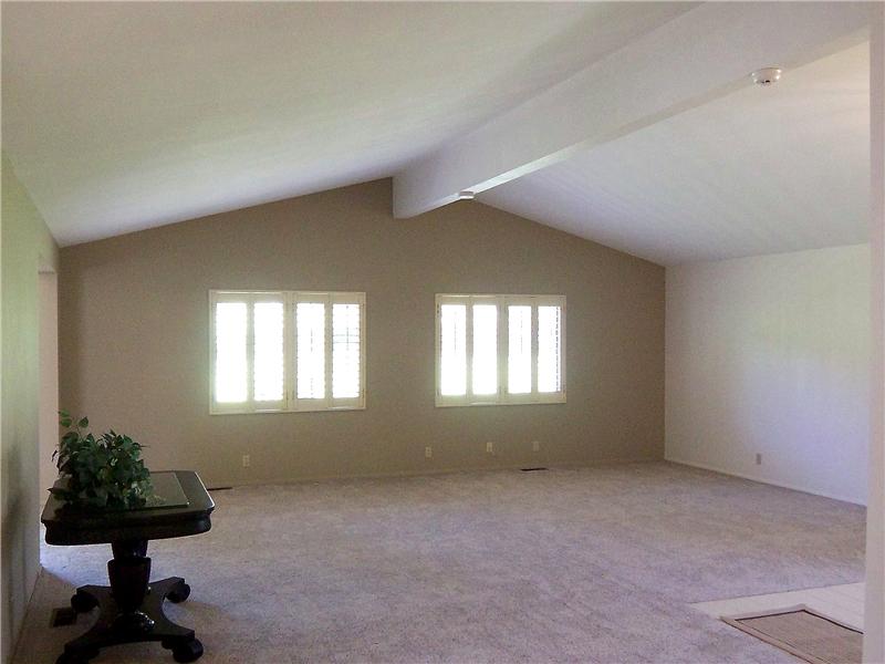 Light and bright living room with plenty of space for multiple seating areas and views of the greenbelt