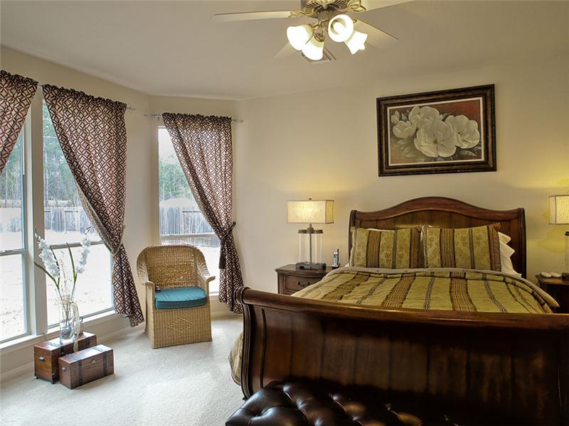 The spacious master bedroom has a ceiling fan.