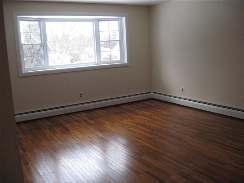 Spacious living room with Bow window and hardwood floors.
