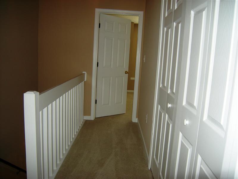 Carpeted hallway on the upper level with laundry closet