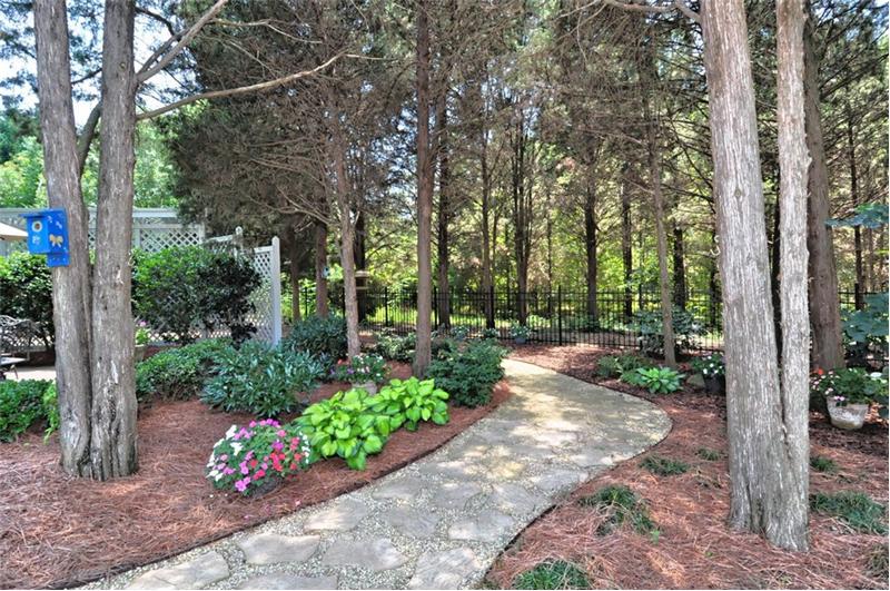 Brick paver walkway through lush, landscaped backyard