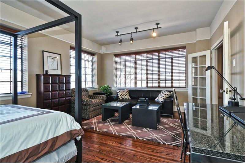 French doors open to living room--large windows with custom blinds in oversized MBR