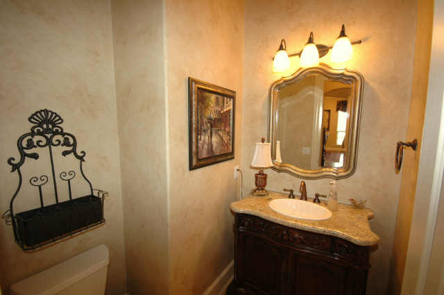 Powder room with furniture sink and granite top.
